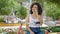 Young beautiful hispanic woman biker talking on smartphone sitting on bench at park