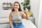 Young beautiful hispanic woman communicate with deaf language sitting on sofa at home