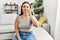 Young beautiful hispanic woman communicate with deaf language sitting on sofa at home