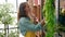 Young beautiful hispanic woman florist organizing shelving at florist