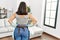 Young beautiful hispanic woman holding diffuser and cloth on back view at home