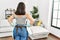 Young beautiful hispanic woman holding diffuser and cloth on back view at home