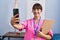 Young beautiful hispanic woman physiotherapist make selfie by smartphone at rehab clinic