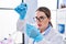 Young beautiful hispanic woman scientist pouring liquid on test tube at laboratory