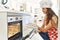 Young beautiful hispanic woman smiling confident opening oven at the kitchen