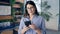 Young beautiful hispanic woman smiling happy using smartphone at the office