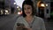 Young beautiful hispanic woman smiling happy using smartphone in the streets at night