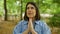 Young beautiful hispanic woman smiling praying at the park in Vienna