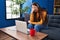 Young beautiful hispanic woman stressed having video call sitting on sofa at home