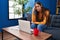 Young beautiful hispanic woman stressed having video call sitting on sofa at home