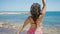 Young beautiful hispanic woman tourist standing backwards dancing at beach