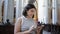 Young beautiful hispanic woman visiting church using smartphone standing at Augustinian Church in Vienna