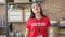 Young beautiful hispanic woman volunteer standing with relaxed face at charity center