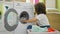 Young beautiful hispanic woman washing clothes at laundry room