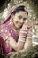 Young beautiful Indian Hindu bride laughing under tree with painted hands raised