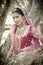 Young beautiful Indian Hindu bride standing under tree