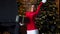 Young beautiful lady in Christmas costume holding gifts near Christmas tree