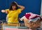 Young beautiful latin woman looking clock hanging clothes on clothesline at laundry room