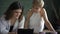 Young beautiful lesbian women are using tablet at table in modern apartment.