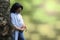 Young beautiful long haired brunette leaning on a bizarre tree and looking at her pregnant belly