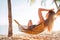 Young beautiful longhaired woman relax in hammok on the sand beach