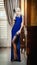 Young beautiful luxurious woman in long elegant dress. Beautiful young blonde woman in blue dress holding a glass of wine