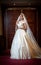 Young beautiful luxurious woman in wedding dress posing in luxurious interior. Gorgeous elegant bride with long veil. Full length