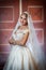 Young beautiful luxurious woman in wedding dress posing in luxurious interior. Gorgeous elegant bride with long veil. Full length