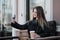 Young beautiful millenial girl in a coat is sitting on an outdor bench with a paper cup of coffee. Autumn or spring day