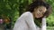 Young beautiful mixed race woman with curly afro hair smiling happily in a green park.