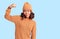 Young beautiful mixed race woman wearing wool sweater and winter hat strong person showing arm muscle, confident and proud of