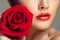 Young beautiful model with red rose near lips