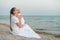 Young beautiful mom sitting on beach and hugging baby. Mothers love and care