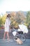 A young and beautiful mother drives a light baby carriage with a child and walks a dog.