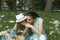 Young beautiful mother with a happy smile on her face with her teenage daughter resting in the park on the grass sniffing flowers.