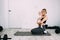 Young beautiful mother with her daughter in her arms sits in the room on the floor after yoga exercises. Doing sports at