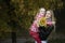 Young beautiful mother holds her litle girl in autumn park looking at the camera