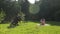 Young beautiful mother in shorts and glasses walks on green lawn with her infant daughter