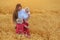 Young beautiful mother with two children in wheat field at sunset. Weekend outdoors