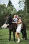 Young beautiful mother in white dress, hat and cowboy boots, petting horse, while her two cute little daughters riding