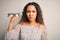 Young beautiful optical woman with curly hair holding vision glasses over white background with a confident expression on smart