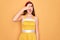 Young beautiful pin up woman wearing 50s fashion vintage dress over yellow background peeking in shock covering face and eyes with