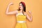 Young beautiful pin up woman wearing 50s fashion vintage dress over yellow background showing arms muscles smiling proud
