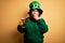 Young beautiful plus size woman wearing green hat celebrating st patricks day drinking beer cover mouth with hand shocked with