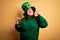 Young beautiful plus size woman wearing green hat celebrating st patricks day drinking beer doing ok sign with fingers, excellent