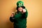 Young beautiful plus size woman wearing green hat celebrating st patricks day drinking beer pointing with finger to the camera and