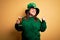 Young beautiful plus size woman wearing green hat celebrating st patricks day drinking beer pointing and showing with thumb up to