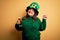 Young beautiful plus size woman wearing green hat celebrating st patricks day drinking beer very happy pointing with hand and