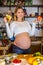 Young beautiful pregnant girl cutting fruits and making smoothie