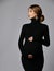 Young beautiful pregnant woman in black dress and massive cross earrings standing and looking down